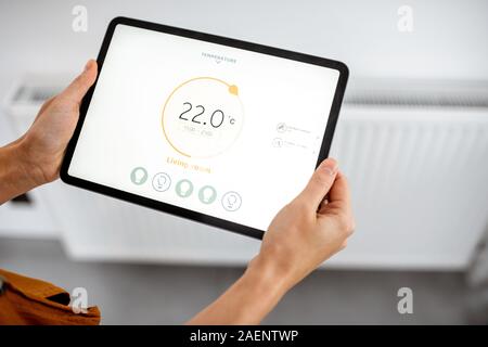 Le contrôle de température de chauffage du radiateur avec un comprimé, close-up avec radiateur sur l'arrière-plan. Concept d'une maison intelligente et l'application mobile pour la gestion des appareils intelligents à la maison Banque D'Images