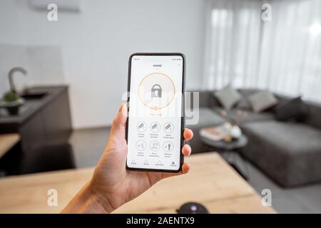 La tenue d'un smartphone avec le programme de la sécurité de l'intérieur a lancé. Concept de contrôle et la gestion de la sécurité à la maison à partir d'un terminal mobile Banque D'Images