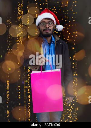 Indian man wearing party clothes in Santa hat avec panier sur fond foncé teint foncé studio Middle Eastern Père Noël Joyeux Noël Banque D'Images