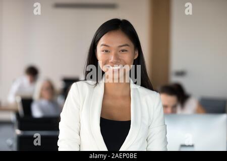 Head shot portrait of smiling Asian businesswoman standing in office Banque D'Images
