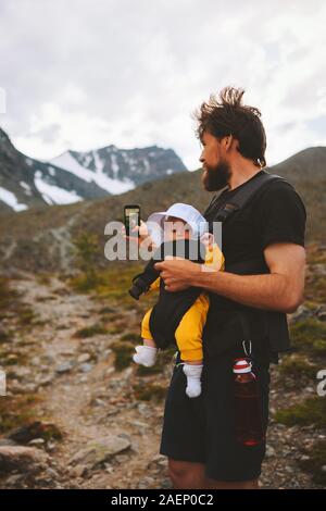 Père avec bébé en tenant par selfies voyage smartphone dans les montagnes famille vacances d'aventure randonnées avec les enfants la vie sain outdoor blogger influen Banque D'Images