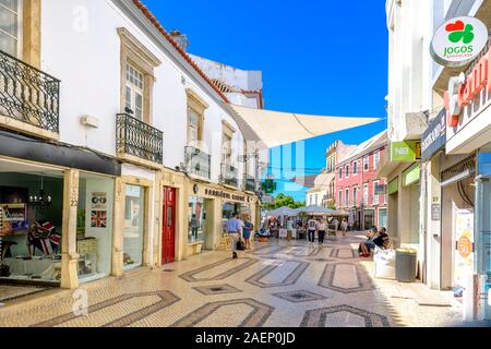 Boutiques de Faro et restaurant en plein air dans une rue pavée traditionnelle avec des pavés portugais traditionnels, centre commercial Calcada Faro, Algarve Portugal. Banque D'Images