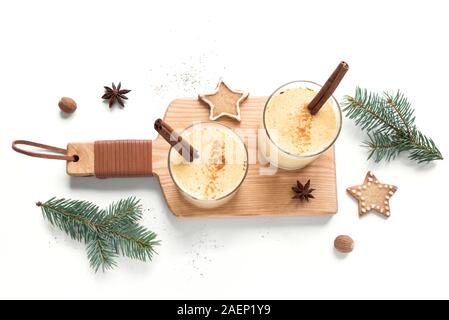 Noël avec un verre de lait de poule de muscade râpée et des bâtons de cannelle pour Noël et vacances d'hiver, isolé sur fond blanc, vue du dessus. Banque D'Images