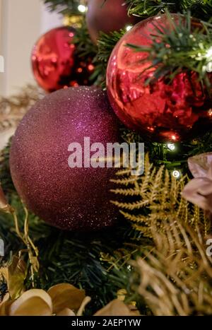 Close Up de sapin de Noël avec des boules rouge violet et or et de décorations. Banque D'Images