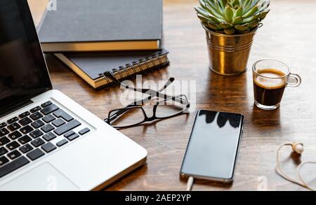 Bureau, espace de travail chaleureux confortable. Ordinateur portable et téléphone mobile sur une table en bois de châtaignier Banque D'Images