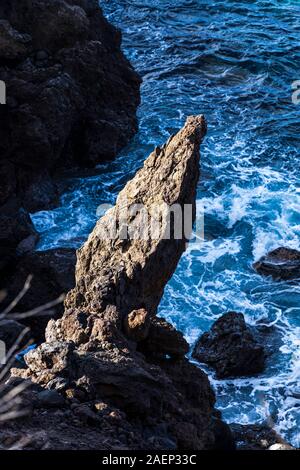 Sunlit jagged provient de roches volcaniques d'une falaise sur la mer tourbillonnante ci-dessous sur la côte ouest de Tenerife, Canaries, Espagne Banque D'Images