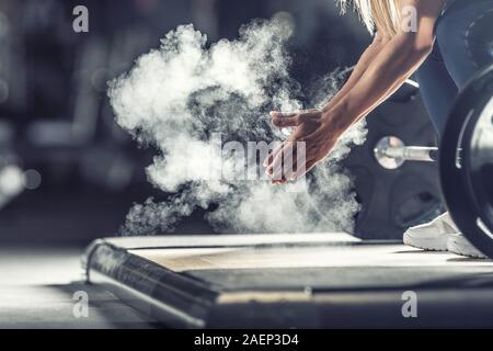 Femme haltérophile musculaire des mains les mains avant d'entraînement d'haltères à la salle de sport avec haltères. Banque D'Images