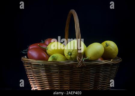 Panier en osier avec fruits d'automne et de citrons sur fond noir Banque D'Images