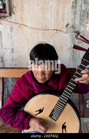 7 mars 2019 : Senior femme chinoise jouant un instrument de musique traditionnel chinois à Jianshui, Yunnan, Chine Banque D'Images