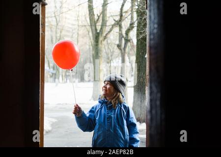 Joyeux garçon debout dans l'embrasure de la tenant à la main ballon rouge sur un bâton Banque D'Images