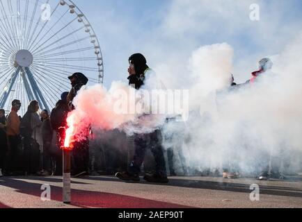 Lyon, France. Dec 10, 2019. La Pyrotechnie burns lors d'une manifestation dans le cadre de grèves et manifestations contre la réforme des retraites en France à la place Bellecour. La grève générale et des manifestations violentes à Lyon également conserver les fans de l'équipe de football Bundesliga RB Leipzig sur leurs orteils. À midi, le mardi, le club a mis en garde ses partisans de ne pas répondre à la Place Bellecour pour un entraînement commun pour le stade. Peu de temps après, il y a eu des affrontements entre manifestants et policiers sur et autour de la place. Les canons à eau et des gaz lacrymogènes ont été utilisés, les hélicoptères de l'encerclé paysage. Credit : dpa Banque D'Images