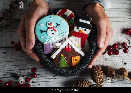 Libre d'un jeune homme de race blanche avec une pile de biscuits de Noël dans ses mains, avec différentes formes et couleurs, comme une maison en pain d'épices, un snow Banque D'Images