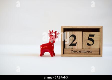 Calendrier en bois Cube affichant la date le 25 décembre avec la céramique figurine renne sur fond blanc. Calendrier de l'Avent, Noël arrière-plan Banque D'Images