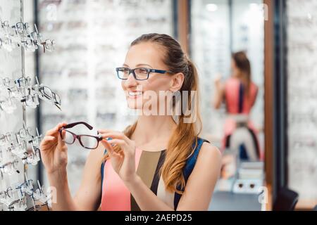 Belle femme de choisir de nouvelles lunettes en magasin Banque D'Images