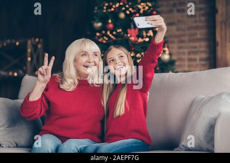 Close-up portrait of attractive cheerful nice heureux joyeux petits granny peu pré-adolescence lycéenne aux cheveux long prendre décisions montrant selfies v-sign à Banque D'Images