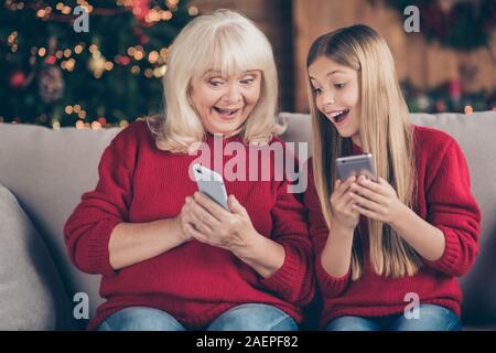 Close-up portrait of attractive cheerful nice heureux granny pré-adolescence lycéenne aux cheveux longs à l'aide de l'envoi de cellules de réception de SMS message Félicitations à Banque D'Images