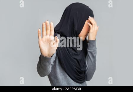 Femme musulmane dans hijab faisant arrêter le geste et couvrant son visage Banque D'Images