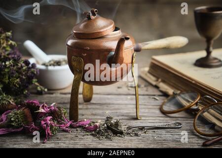 Ancienne théière bouillante, sec coneflowers, vieux livres, lunettes rétro et herbes médicinales. Banque D'Images