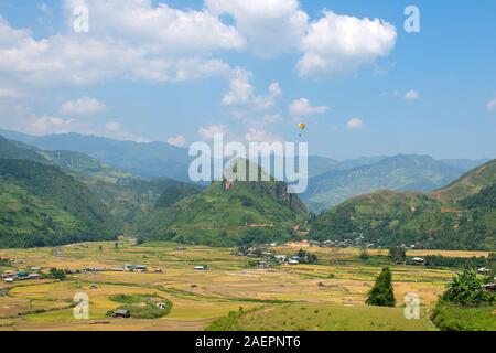 Le parapente survole les champs de terrasses de riz vert, brun, jaune et doré de la vallée de Tu le, au nord-ouest du Vietnam Banque D'Images