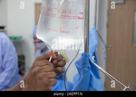 Mains d'un technicien contrôle Hôpital Theatre un sac de solution saline dans un théâtre d'opération des hôpitaux avant une opération. Banque D'Images