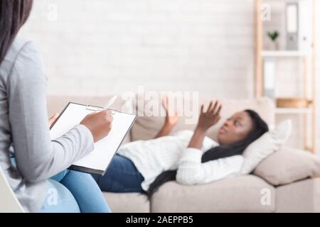 Jeune femme noire couchée sur table à un bureau du psychothérapeute Banque D'Images