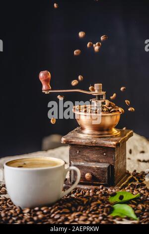 Café en grains tombent sur main vintage en bois broyeur de café. Parfumé de broyage du café fraîchement torréfié Banque D'Images