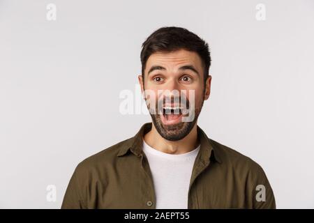 C'est hilarant. Amusé et s'est demandé, excité barbu attrayant mâle adulte en manteau, regarder à gauche et rire à drôle de cause, smiling, stupéfait, assister à Banque D'Images