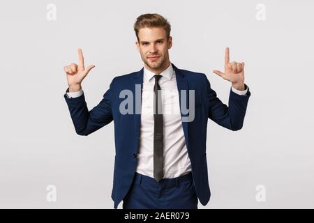 La confiance, concept d'affaires et d'entreprise. Séduisant jeune homme barbu, l'homme en costume, pointant vers le haut et souriant avec appareil photo look dynamique Banque D'Images