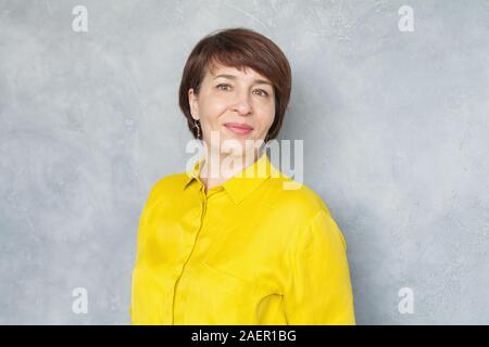 Femme d'affaires d'âge moyen heureux sur fond gris, portrait Banque D'Images