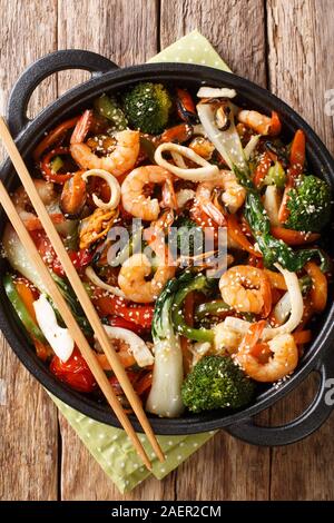 Sauté de fruits de mer avec le brocoli, le bok choy, les carottes, le poivron close-up dans une casserole sur la table. Haut Vertical Vue de dessus Banque D'Images