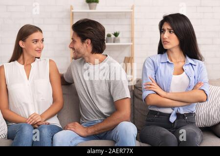 Girl Petit ami flirter avec Woman Sitting on Sofa Banque D'Images