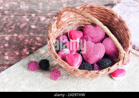 Chewy candy sous la forme de coeurs et les framboises dans un panier Banque D'Images