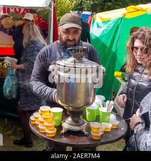 Adygea, Russie - le 21 septembre 2019 : un homme barbu se trouve à la table avec un samovar et pots de miel et de thé fait pour les touristes au fromage Adyghe Banque D'Images