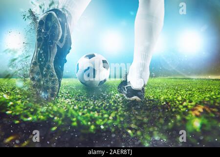 Scène de nuit football match avec gros plan d'une chaussure de soccer frapper la balle Banque D'Images