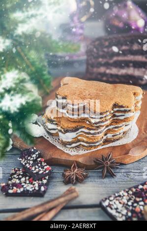 Gâteau de couche se trouve sur la table de vacances de Noël. Des bonbons en sucre, chocolat se trouvent sur la surface en bois de la table. Banque D'Images