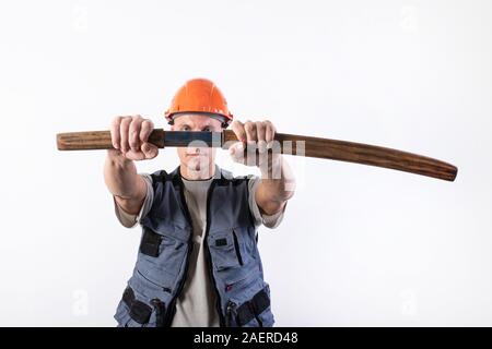 Le constructeur tire un katana de son fourreau, en face de lui. Réparateur portant un casque et des vêtements de travail. Banque D'Images