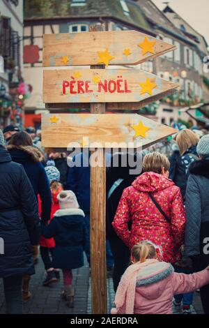 Ribeauvillé, Alsace, France - 8 décembre 2019 : panneau en bois montrant dirrection à Santa Claus (Père Noël). Foule dans les rues de l'ancien français Banque D'Images