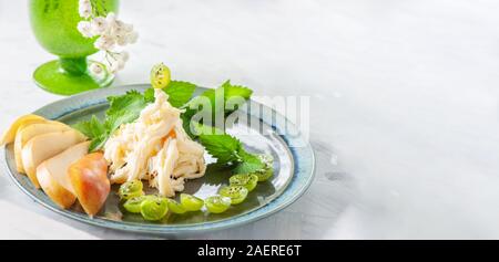 Soft blanc traditionnel fromage Cecil fibreux se trouve sur une plaque. Le fromage est décoré avec des morceaux de poire mûre et de groseilles. L'espace de copie, la bannière. Banque D'Images