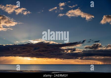 Coucher du soleil sur la mer d'Irlande de Muro, au nord du Pays de Galles, avec des rayons de soleil et nuages Banque D'Images