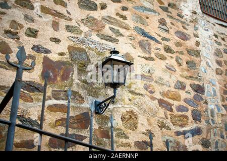 Façade en pierre avec une lanterne en fonte noir pour l'éclairage extérieur. Parador de Guadalupe, à l'ouest de l'Espagne. Banque D'Images