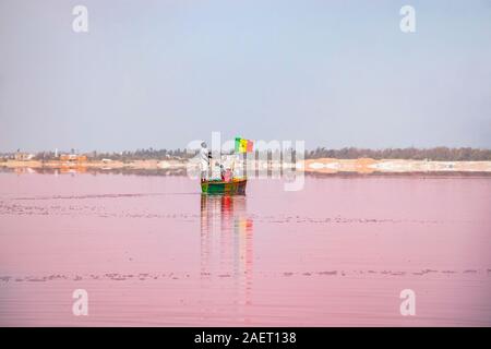 LAC ROSE, AU SÉNÉGAL - Apr 22, 2019 : un homme porte des touristes sur un bateau en bois sur un lac rose, près de la ville de Dakar. Il s'agit d'un sel Lac Retba. Les sections locales Banque D'Images