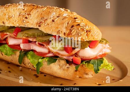 Sandwich avec jambon, cornichons, tomates fraîches et salade verte sur fond de bois Banque D'Images