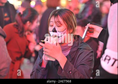 Une personne met sur le rouge à lèvres à l'aide de son téléphone dans une rue de la ville de Shenyang, au nord-est de la Chine, la province de Liaoning, 31 octobre 2019. Banque D'Images