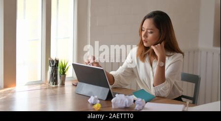 Jeune professionnel businesswoman se concentrant sur son projet avec tablette numérique dans la salle de bureau confortable Banque D'Images