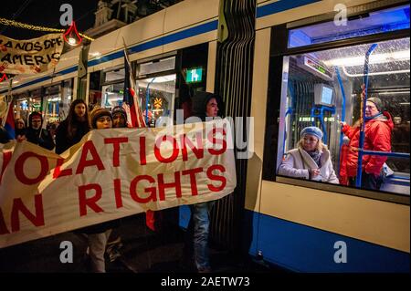 Amsterdam, Pays-Bas. Dec 10, 2019. Les manifestants avec une bannière à côté d'un bus au cours de la marche.sur la Journée des droits de l'homme internationaux, plusieurs plates-formes d'Amérique latine a organisé une marche à travers les rues dans le centre d'Amsterdam pour protester contre les violations des droits de l'homme en Amérique latine. La marche a débuté à la place du Dam à Waterlooplein où les lumières pour les victimes ont été activés. Credit : SOPA/Alamy Images Limited Live News Banque D'Images