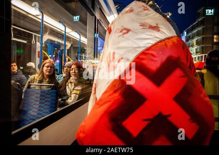 Amsterdam, Pays-Bas. Dec 10, 2019. Les gens sur un bus à la recherche sur les manifestants lors de la marche.sur la Journée des droits de l'homme internationaux, plusieurs plates-formes d'Amérique latine a organisé une marche à travers les rues dans le centre d'Amsterdam pour protester contre les violations des droits de l'homme en Amérique latine. La marche a débuté à la place du Dam à Waterlooplein où les lumières pour les victimes ont été activés. Credit : SOPA/Alamy Images Limited Live News Banque D'Images