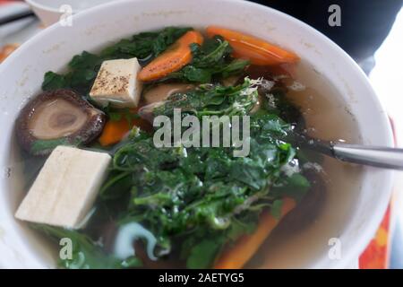 Un bol de soupe de légumes avec des champignons, tofu, carottes, légumes verts et servi dans un restaurant végétalien à Ho Chi Minh Ville, Vietnam Banque D'Images