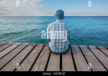 Mer Man relaxing on pier Banque D'Images