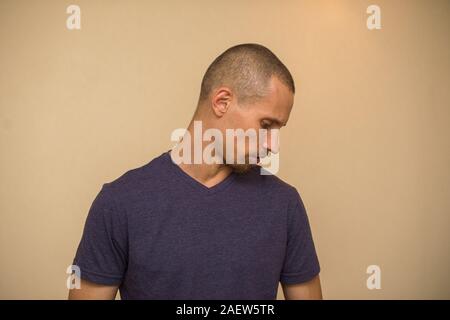 Beau barbu brutale pose en blanc T-shirt violet sur fond beige clair. Banque D'Images