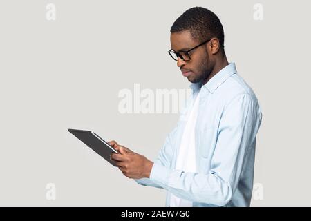Vue de côté les jeunes afro-américains réfléchis guy holding digital tablet. Banque D'Images